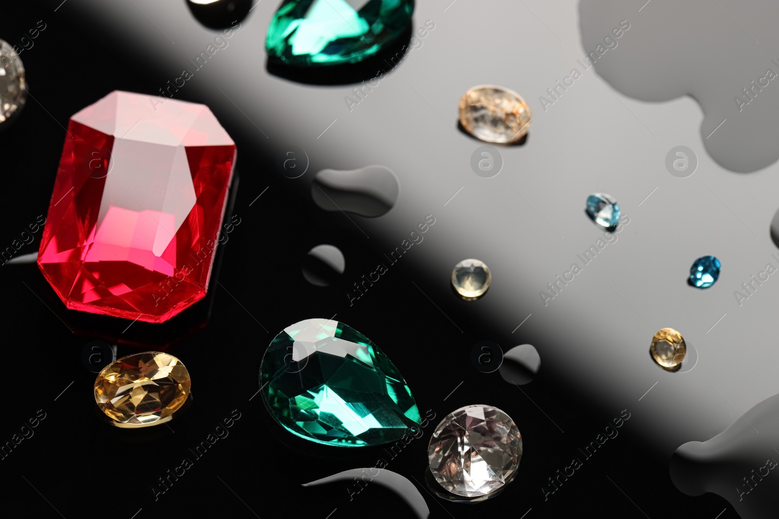 Photo of Different beautiful gemstones for jewelry on dark surface with drops