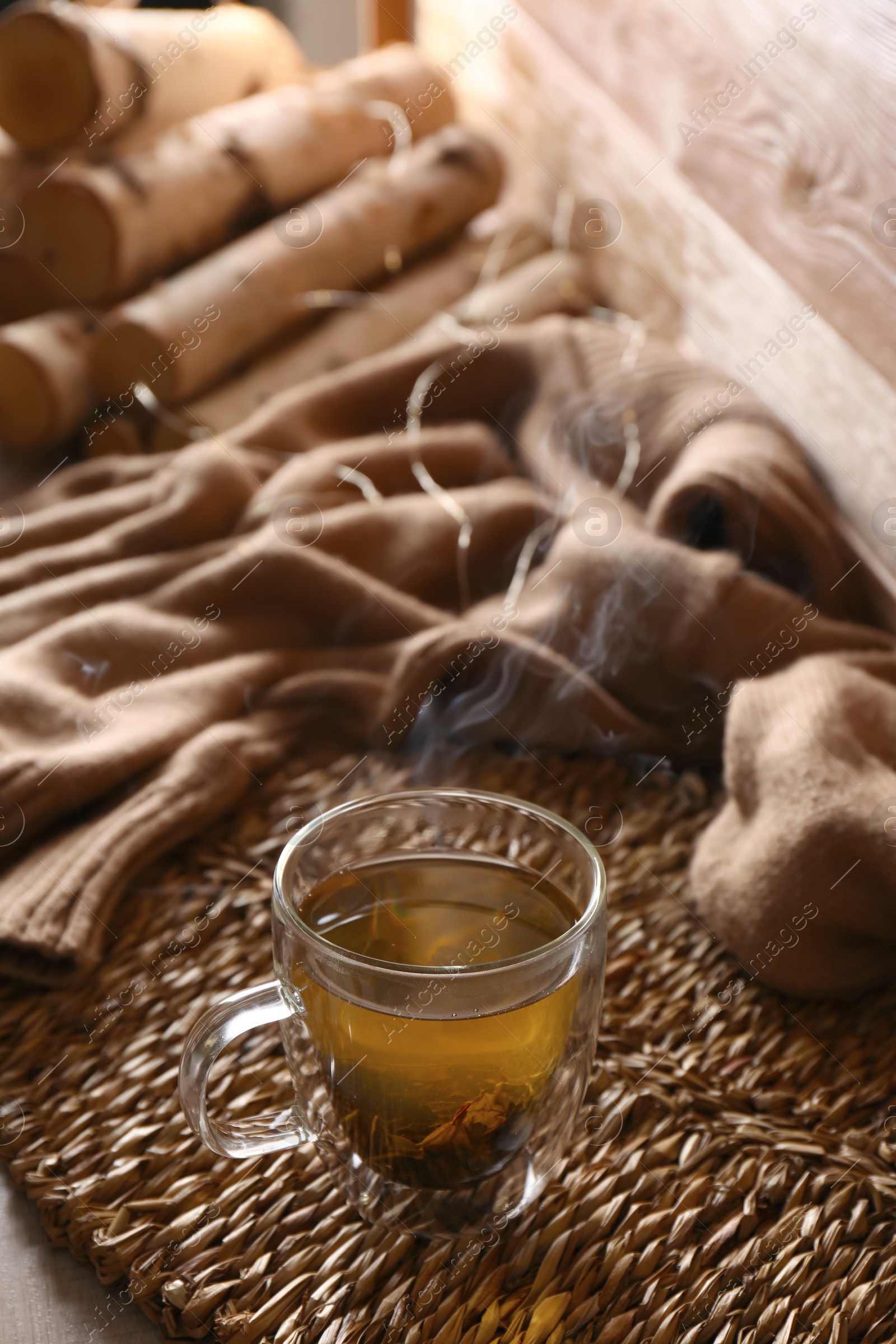 Photo of Wicker mat with freshly brewed tea in room. Cozy home atmosphere