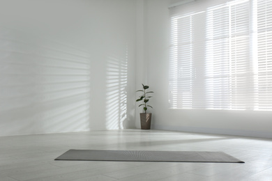 Unrolled grey yoga mat on floor in room. Space for text