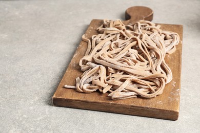 Photo of Uncooked homemade soba with wooden board on light table