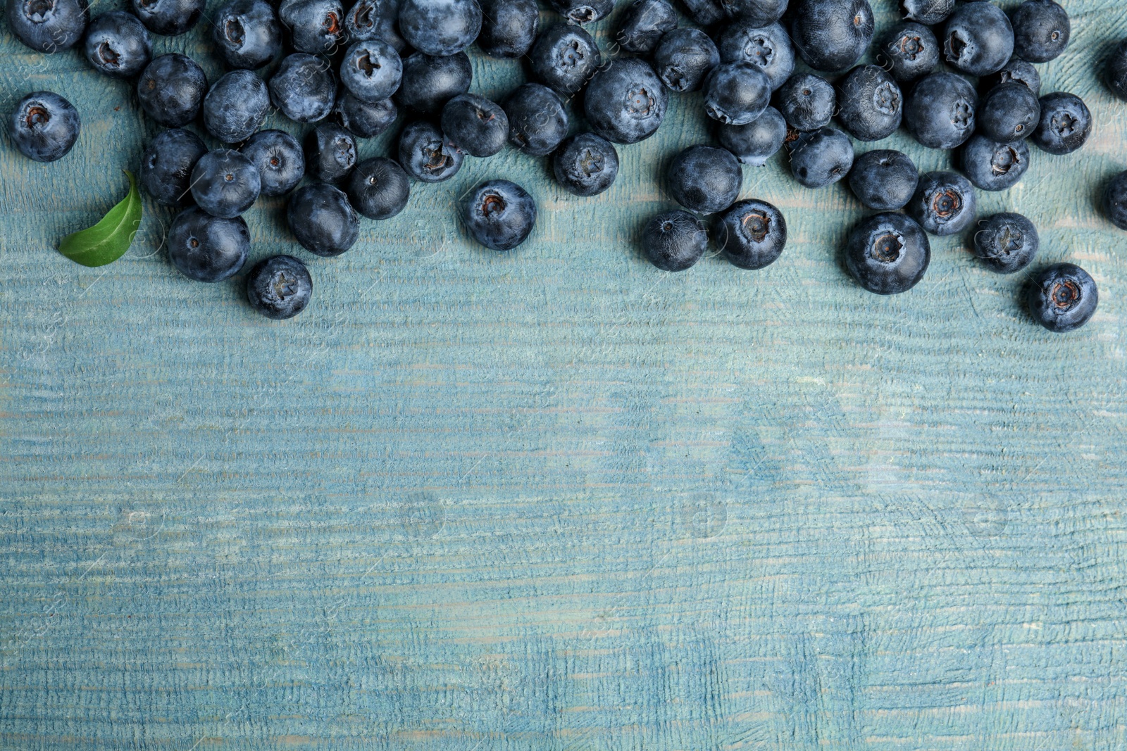 Photo of Fresh ripe blueberries on wooden table, flat lay. Space for text