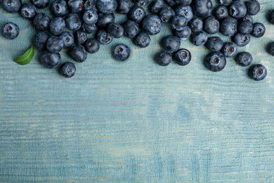 Fresh ripe blueberries on wooden table, flat lay. Space for text