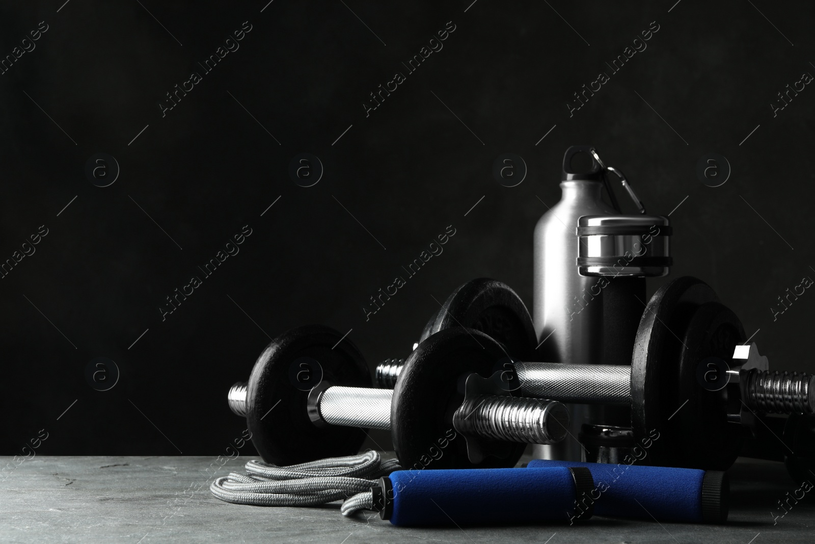 Gym equipment and accessories on stone floor against dark background Photo of Gym equipment and accessories on stone floor against dark background