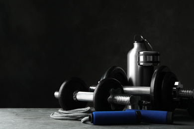 Photo of Gym equipment and accessories on stone floor against dark background