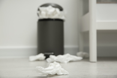 Photo of Used paper tissue on wooden floor indoors, closeup