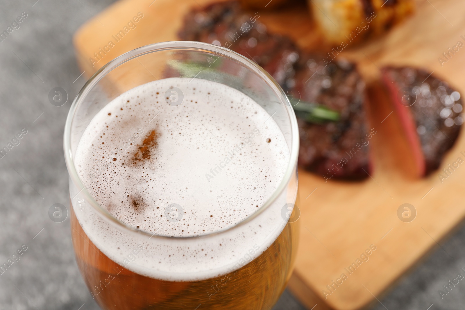 Photo of Glass of tasty beer on grey table, closeup