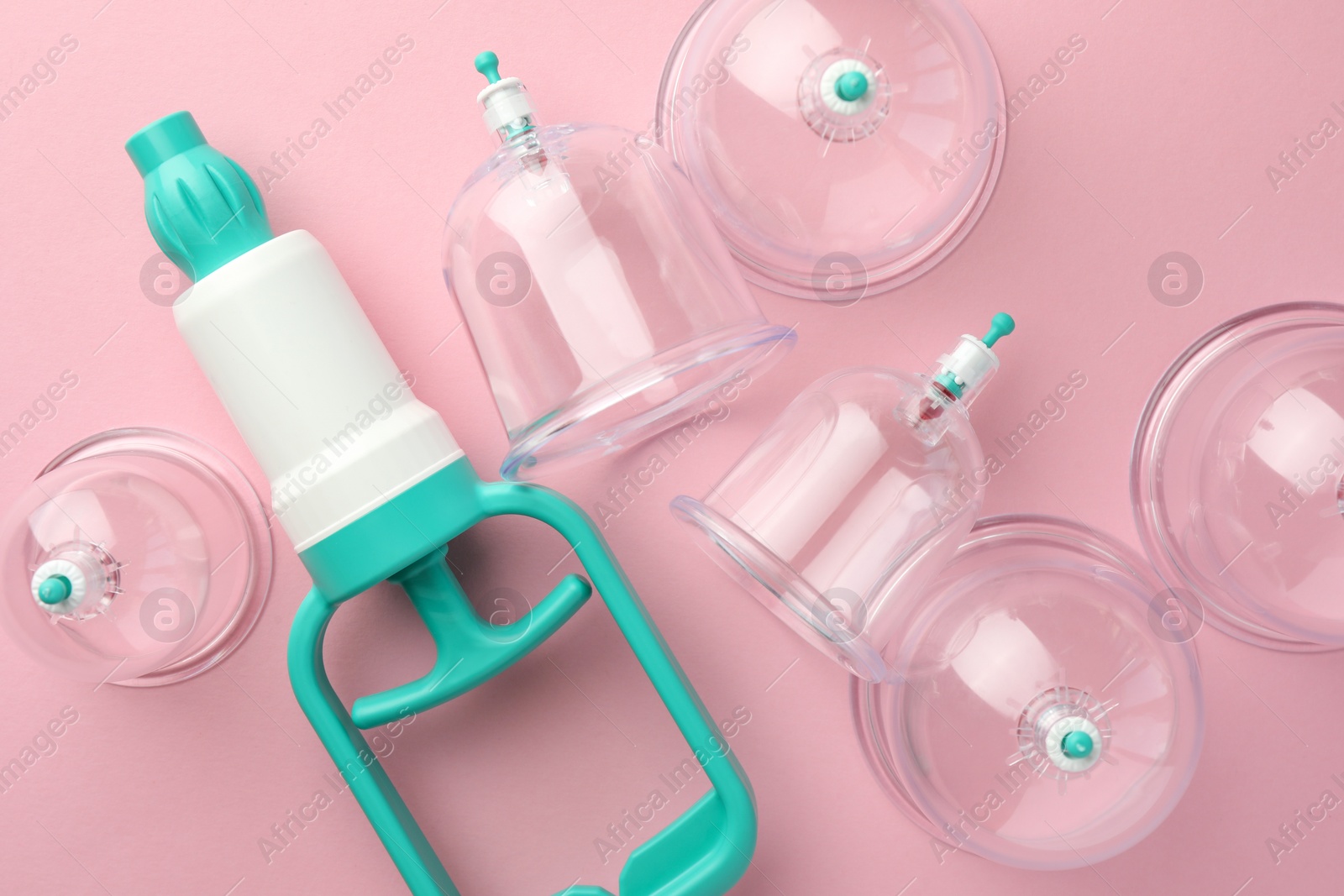 Photo of Plastic cups and hand pump on pink background, flat lay. Cupping therapy