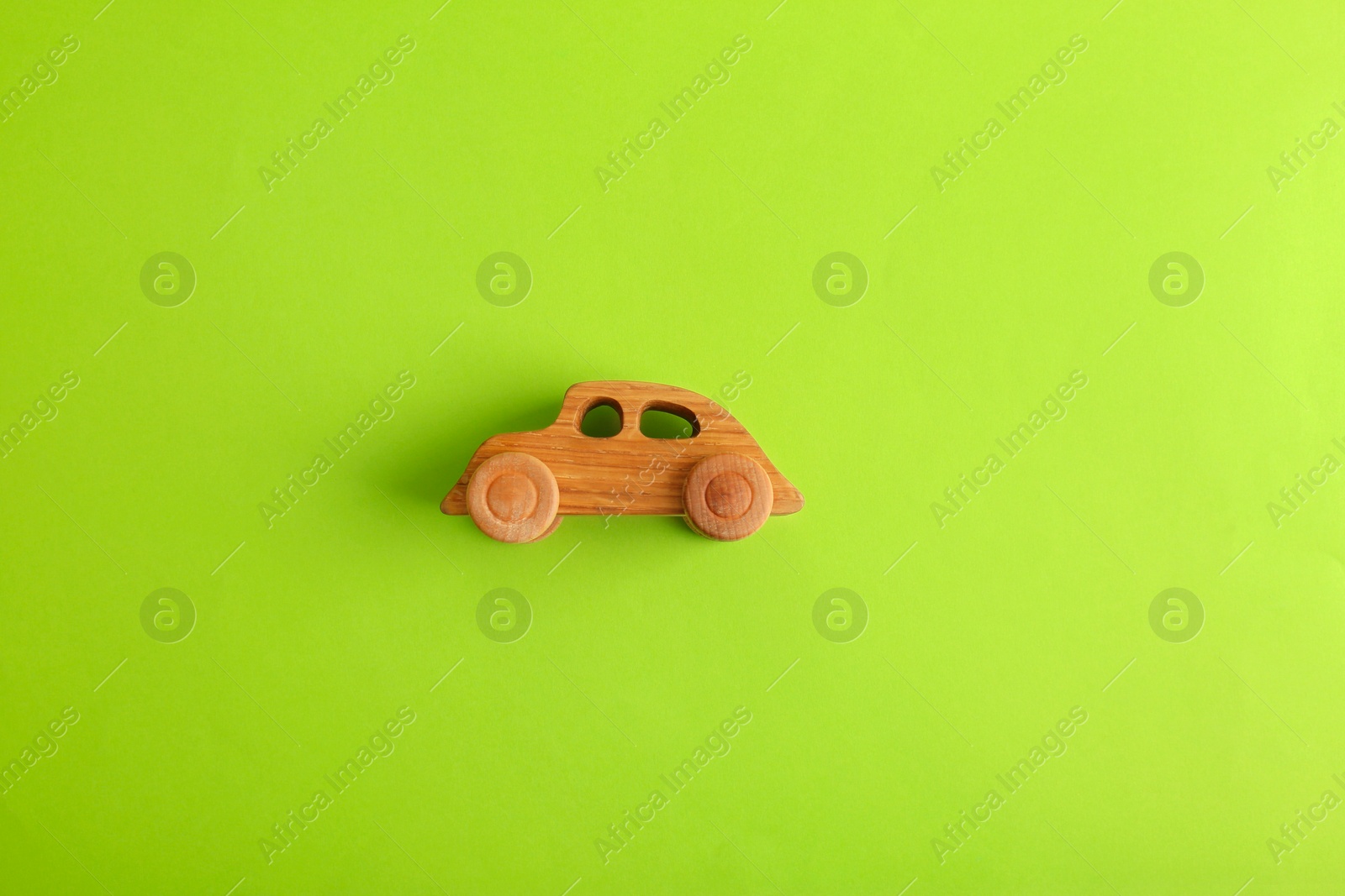 Photo of Wooden toy car on light green background, top view
