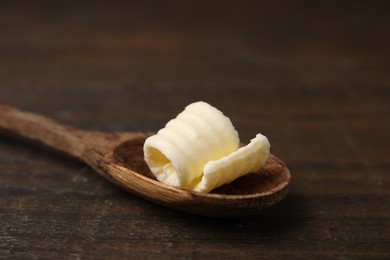 Photo of Tasty butter curl and spoon on wooden table, closeup