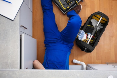 Professional plumber with set of tools working indoors, top view