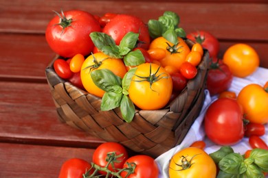 Photo of Different sorts of tomatoes with basil on wooden table