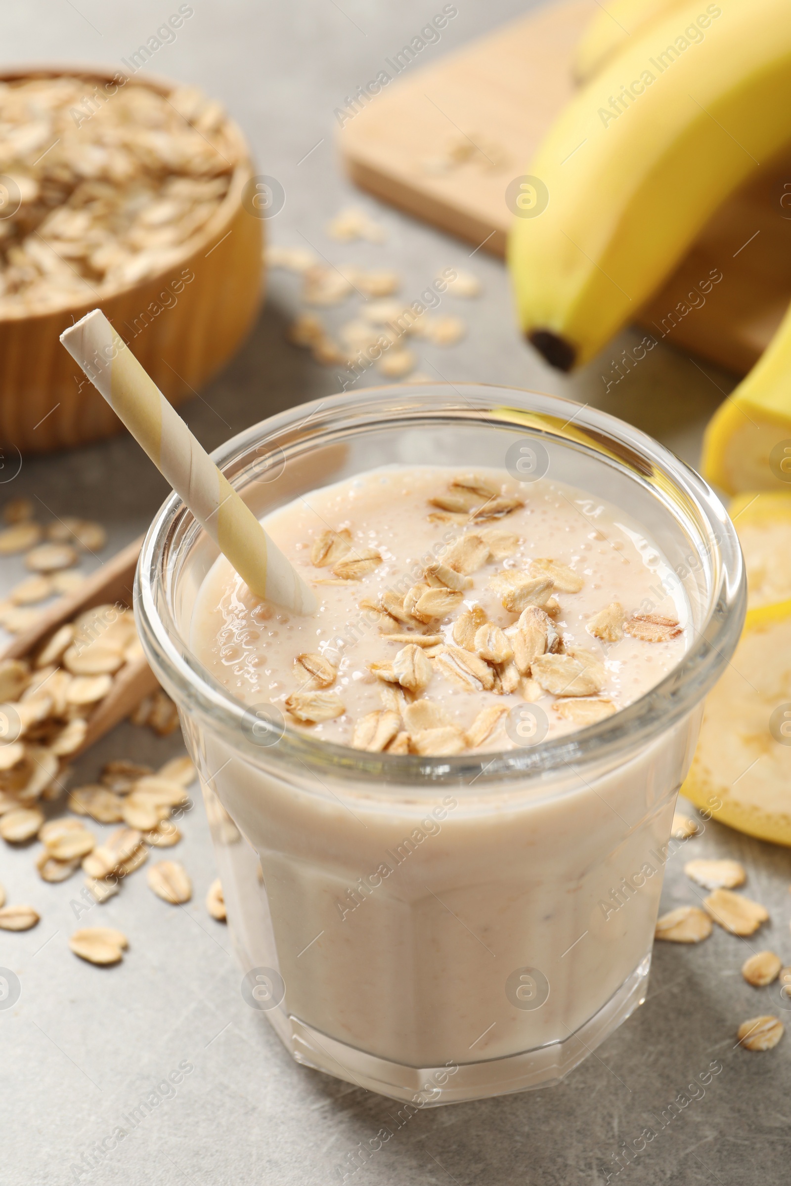 Photo of Glass of tasty banana smoothie with oatmeal on light grey table