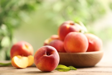 Photo of Fresh sweet peaches on wooden table outdoors