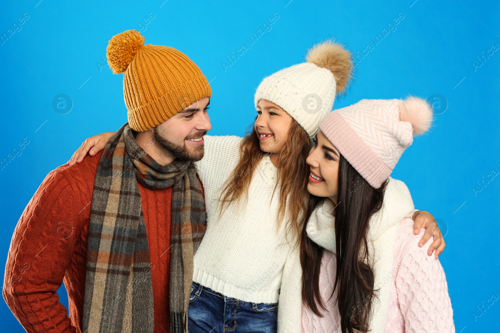 Photo of Happy family in warm clothes on blue background. Winter vacation