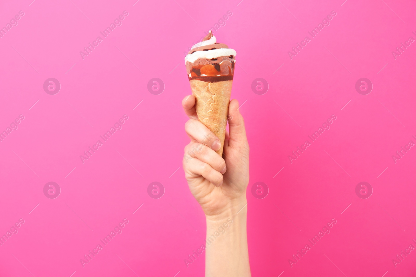 Photo of Woman holding yummy ice cream on color background. Focus on hand