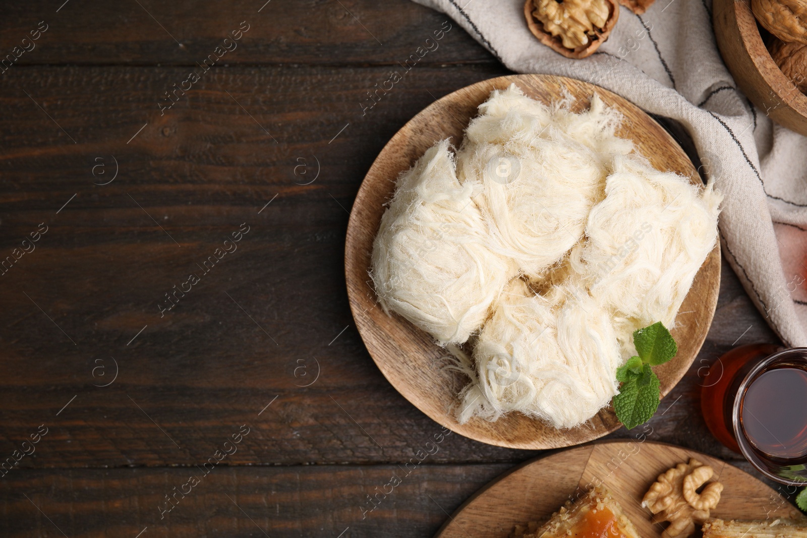 Photo of Eastern sweets. Tasty Iranian pashmak and tea on wooden table, flat lay. Space for text