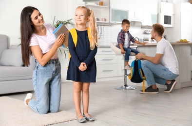 Photo of Young parents helping little children to prepare for school at home