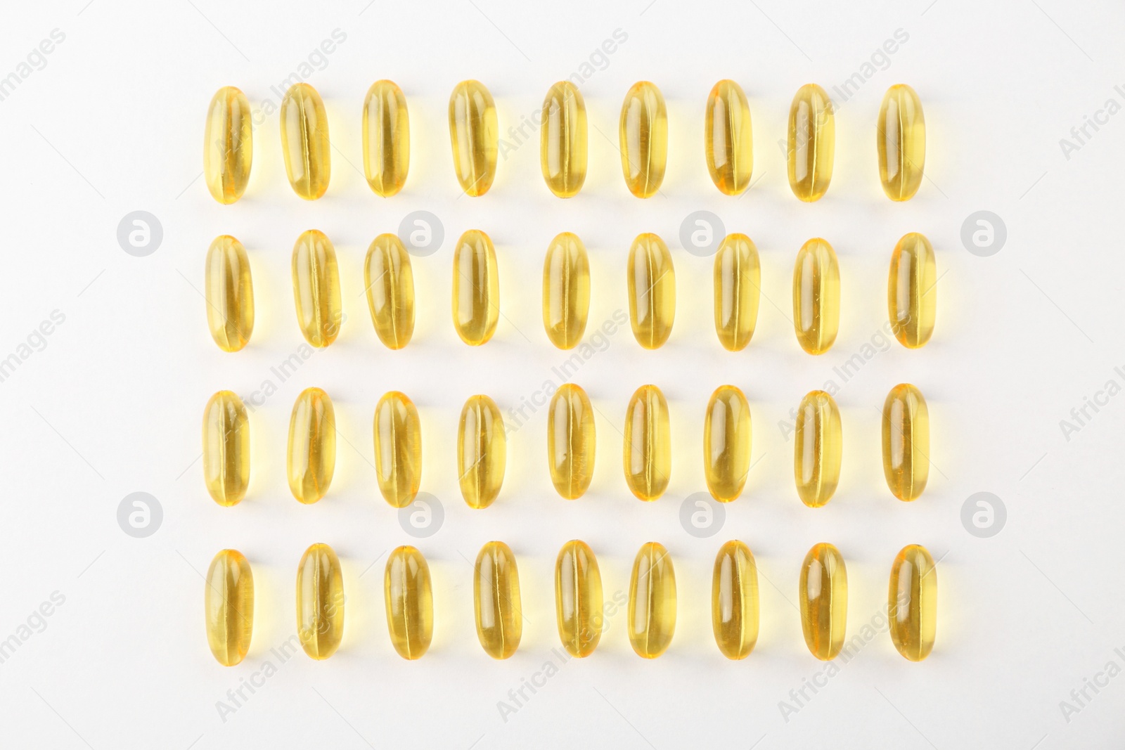 Photo of Yellow vitamin capsules on white background, flat lay