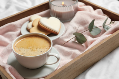 Wooden tray with coffee and cookies on bed. Romantic breakfast