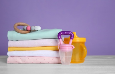 Children's accessories and stack of clothes on white wooden table