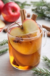 Hot mulled cider and fir branches on white wooden table, closeup