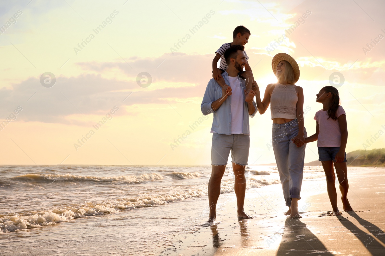 Photo of Happy family walking on sandy beach near sea