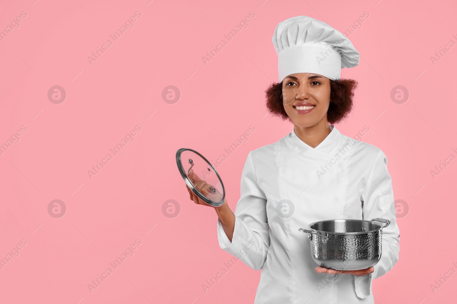 Photo of Happy female chef in uniform holding cooking pot on pink background. Space for text