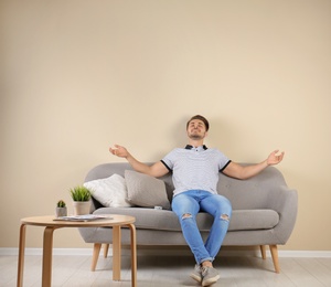 Happy young man with air conditioner remote at home