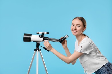 Photo of Happy astronomer with telescope on light blue background