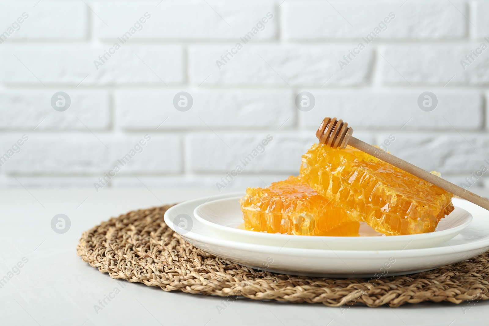 Photo of Natural honeycombs with tasty honey and dipper on white table, space for text