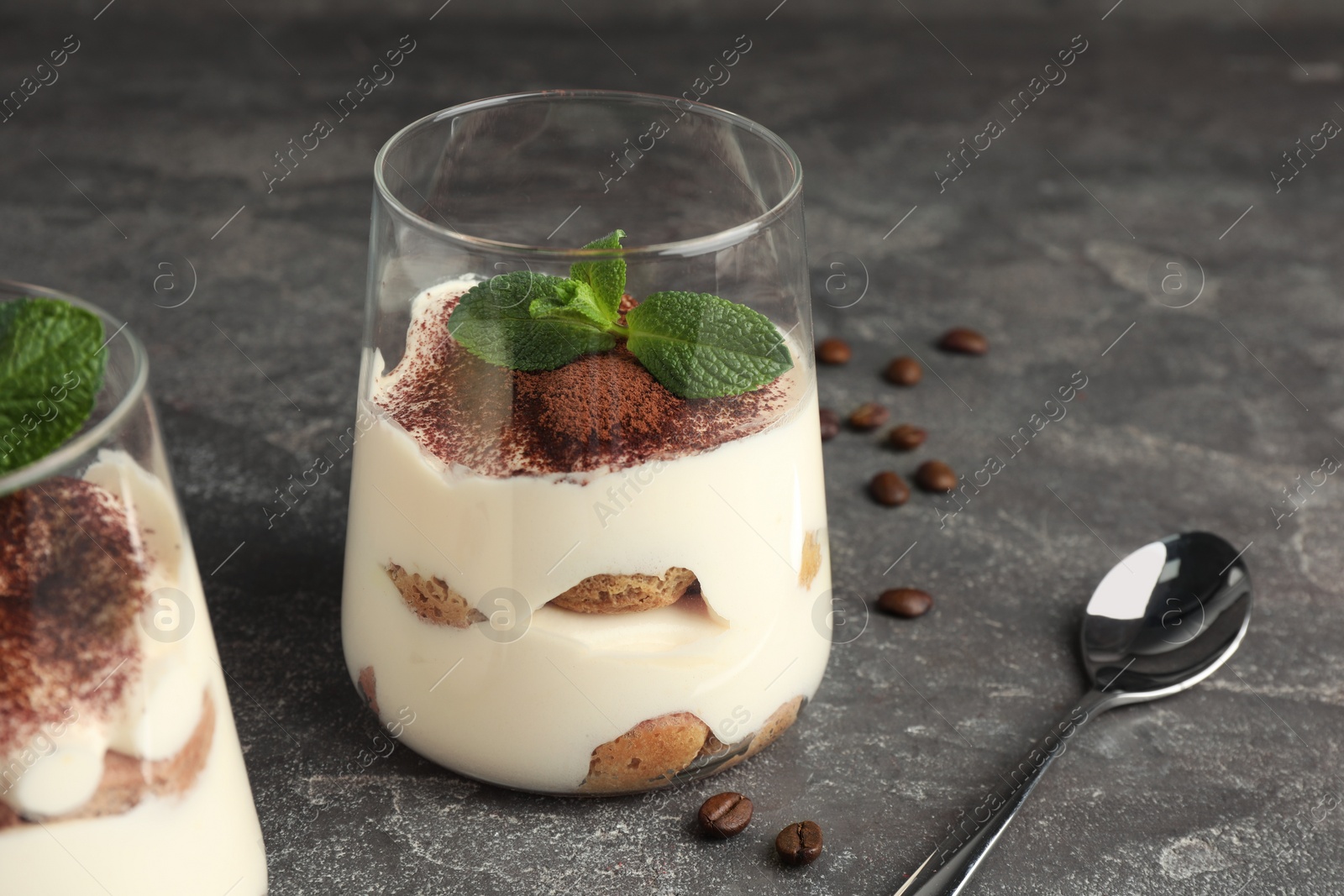 Photo of Delicious tiramisu with mint in glass on grey table