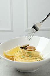 Photo of Eating tasty capellini with mussels and lemon at light grey table, closeup. Exquisite presentation of pasta dish