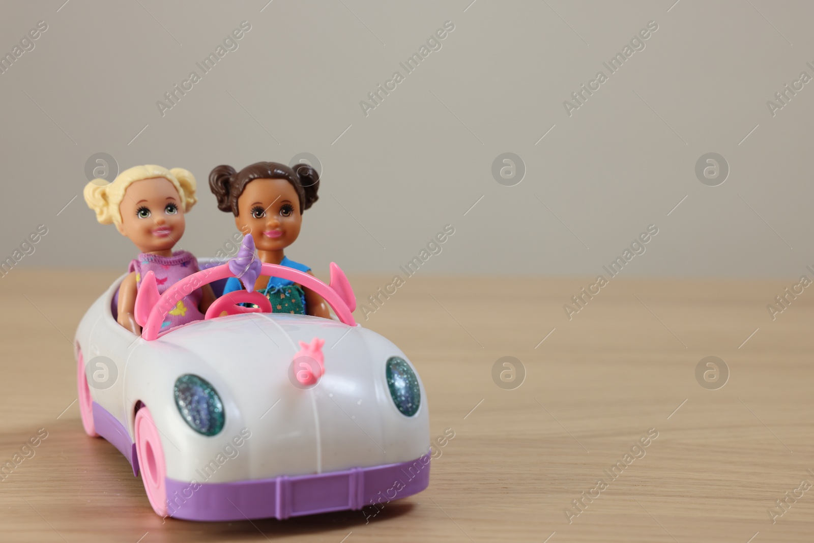 Photo of Leiden, Netherlands - September 20, 2023: Beautiful Chelsea dolls in toy car on wooden table against light background, space for text