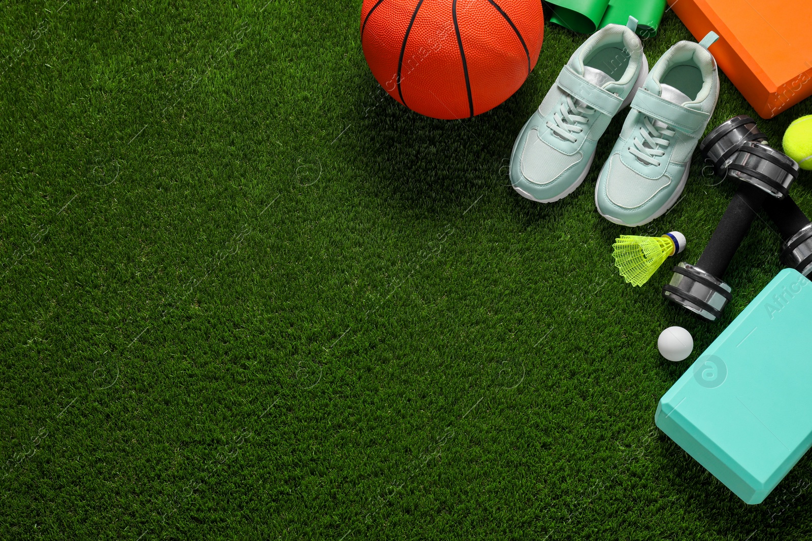 Photo of Different sport tools on green grass, flat lay. Space for text