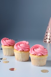 Delicious cupcakes with bright cream and confetti on light background, space for text