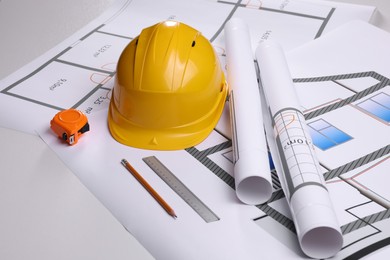 Photo of Construction drawings, safety hat, tape measure, pencil and ruler on white background