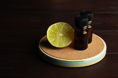 Bottles of essential oil and lime on wooden table