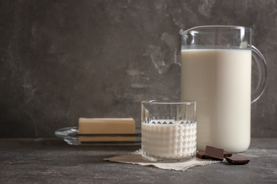 Glass and jug with milk on grey table