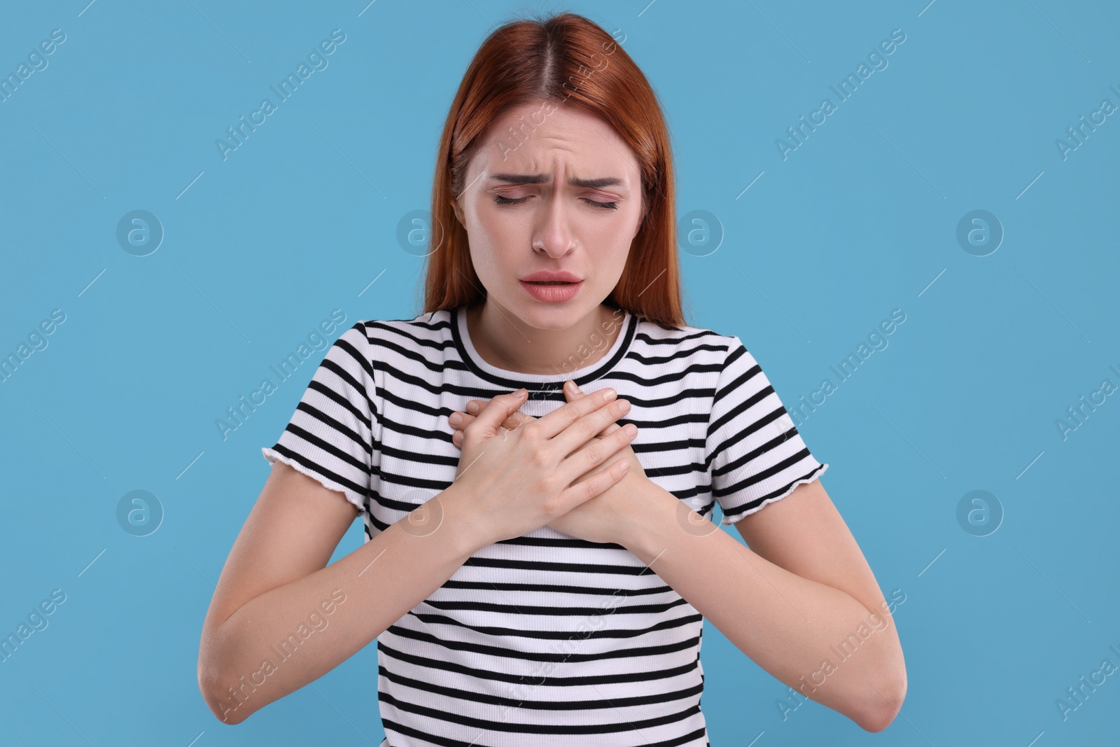 Photo of Woman coughing on light blue background. Cold symptoms