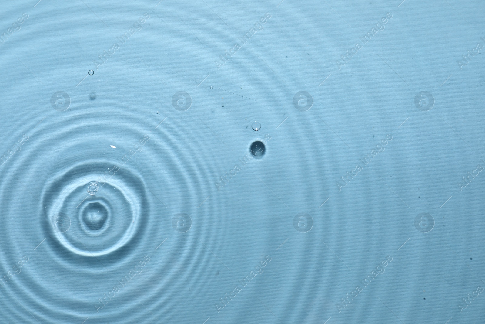 Photo of Rippled surface of clear water on light blue background, top view