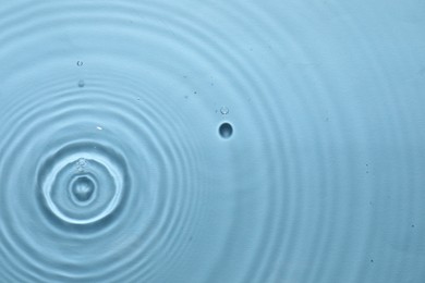 Photo of Rippled surface of clear water on light blue background, top view