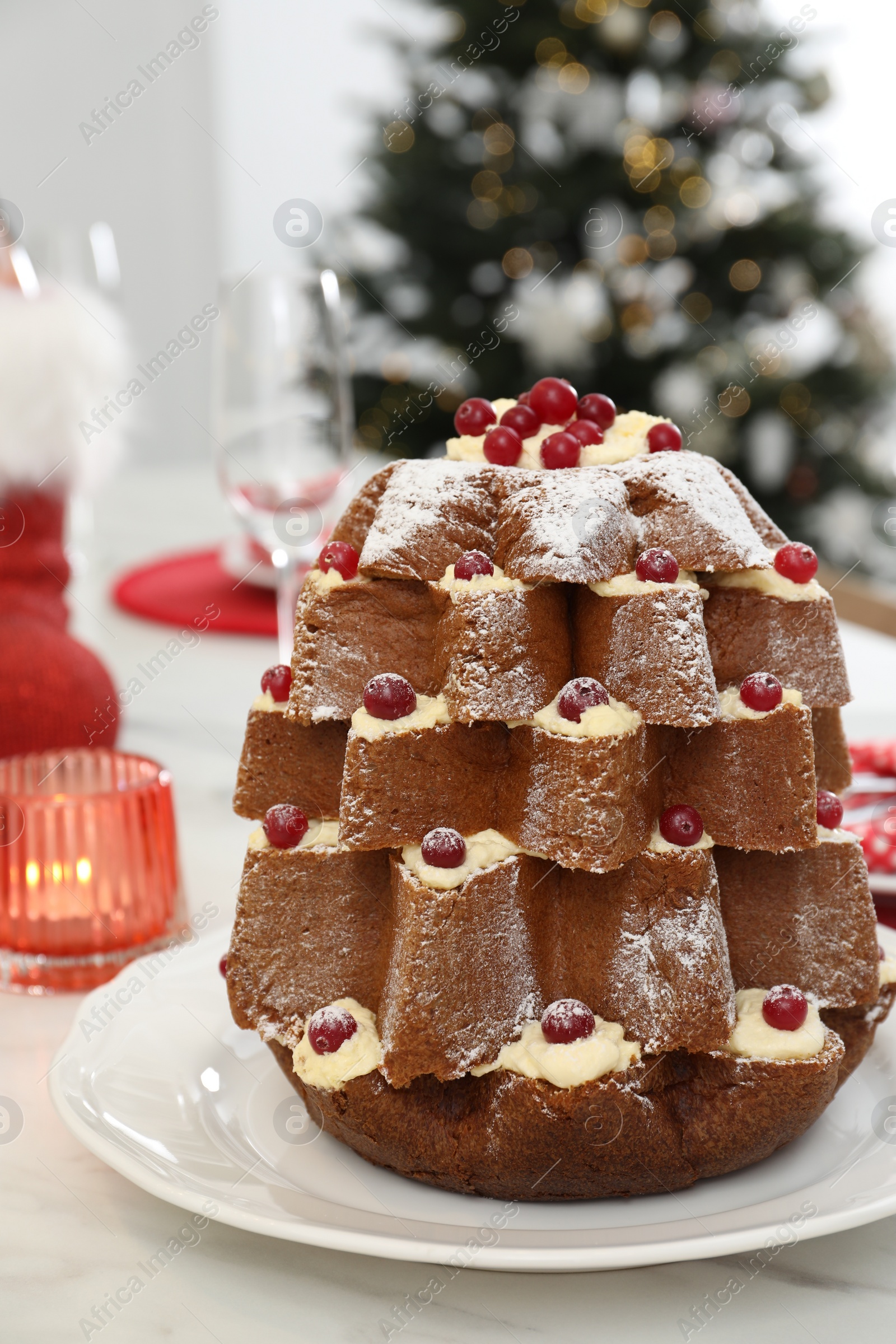 Photo of Delicious Pandoro Christmas tree cake decorated with powdered sugar and berries on white marble table