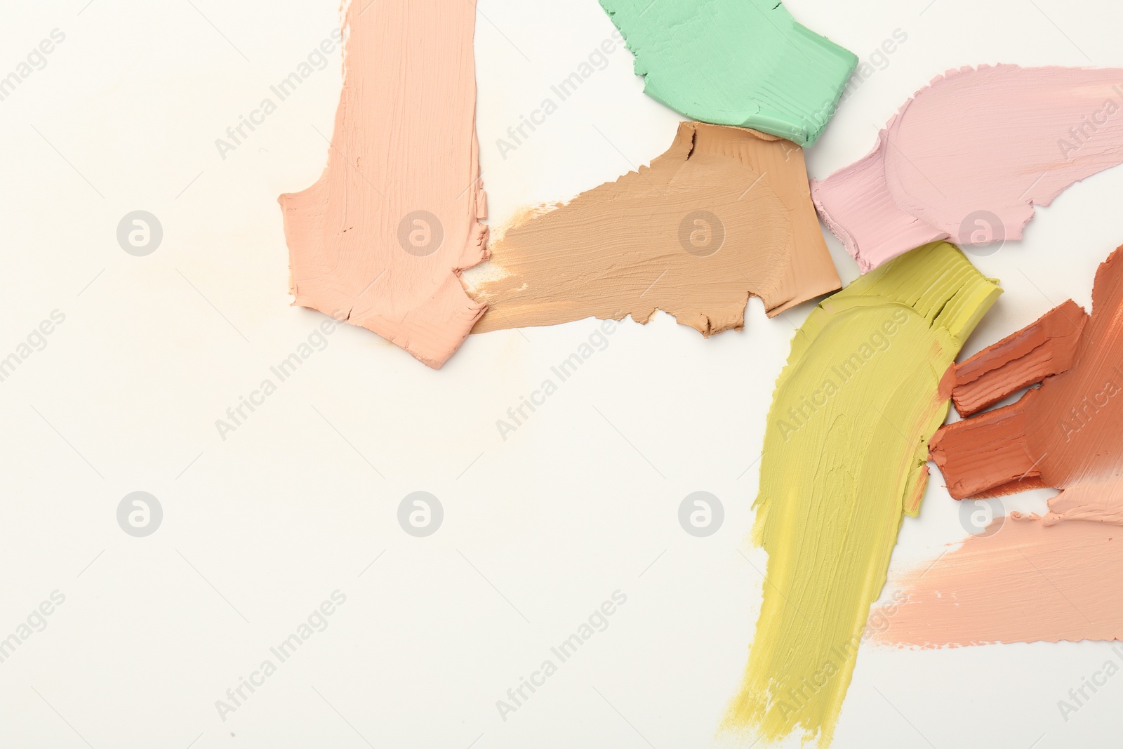 Photo of Samples of different color correcting concealers on white background, top view