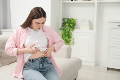 Photo of Diabetes. Woman making insulin injection into her belly on sofa at home, space for text