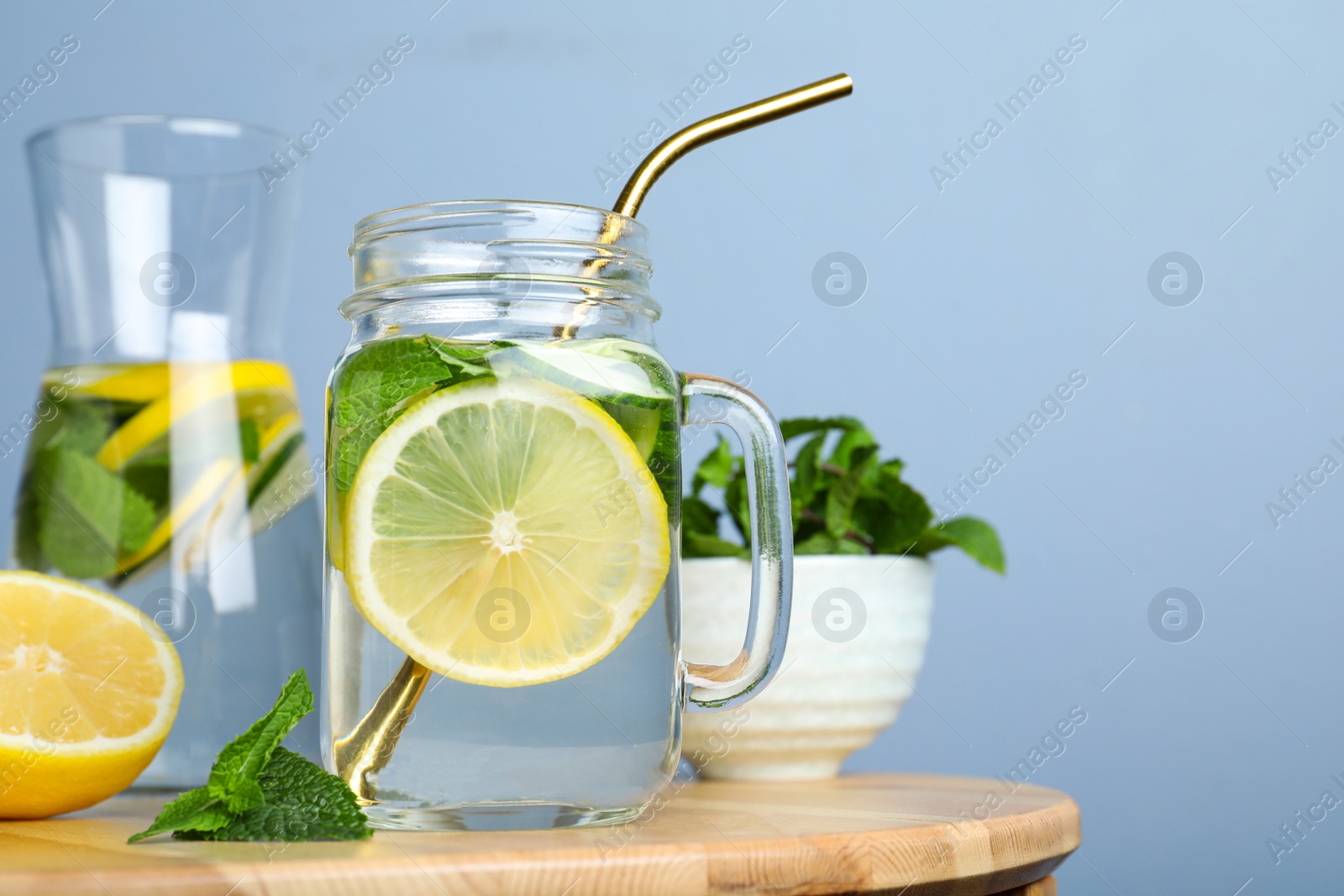 Photo of Refreshing water with cucumber, lemon and mint on wooden table. Space for text