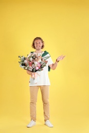 Photo of Young handsome man with beautiful flower bouquet on yellow background