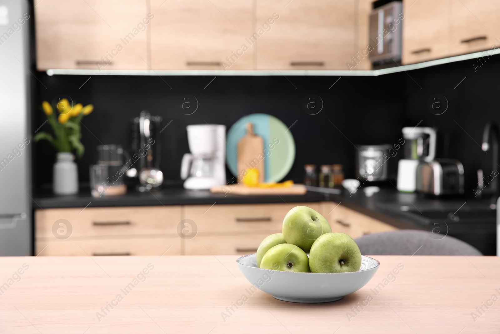 Photo of Fruit bowl with apples on table in kitchen, selective focus