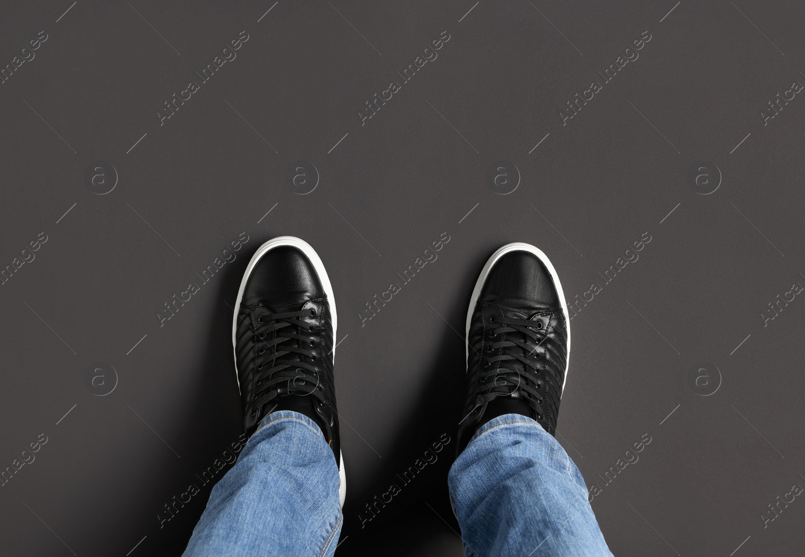 Photo of Man in black leather shoes standing on dark grey background, top view