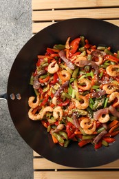 Photo of Shrimp stir fry with vegetables in wok on grey table, top view