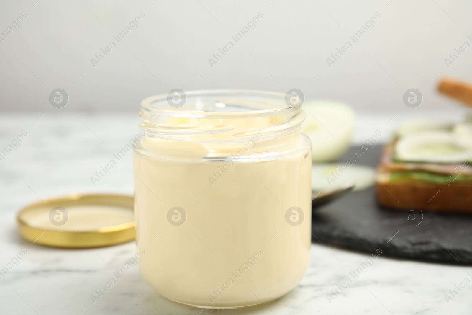 Photo of Jar of delicious mayonnaise on white marble table